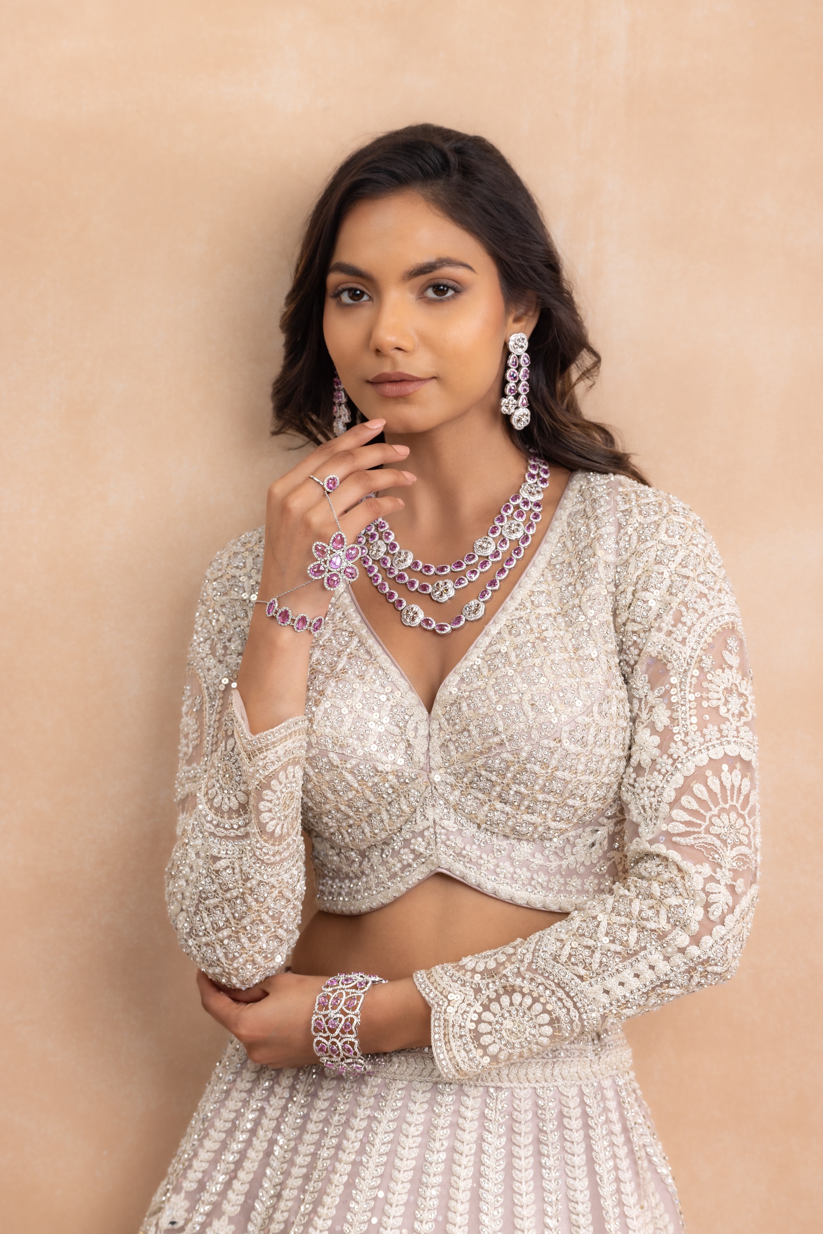 Three-strand rose-pink and diamond necklace worn with a matching cuff, drop earrings and hand ornament